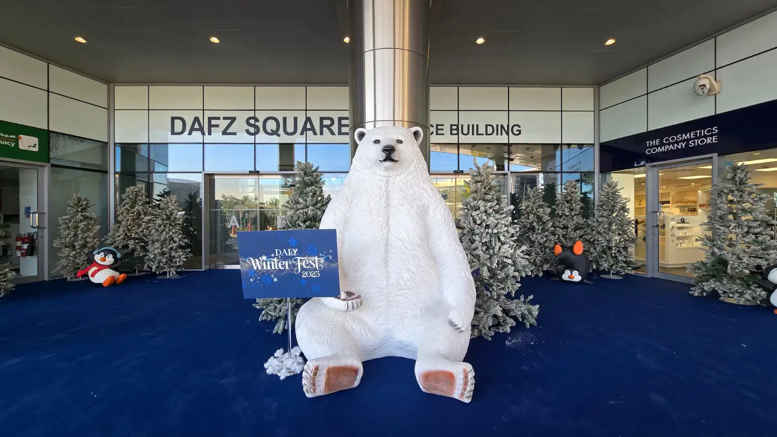 ديكور مدخل مهرجان الشتاء في DAFZ مع مجسم دب قطبي وبطاريق وأشجار مغطاة بالثلج في دبي
